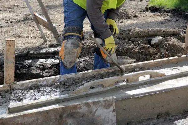A construction worker pouring concrete while building a home