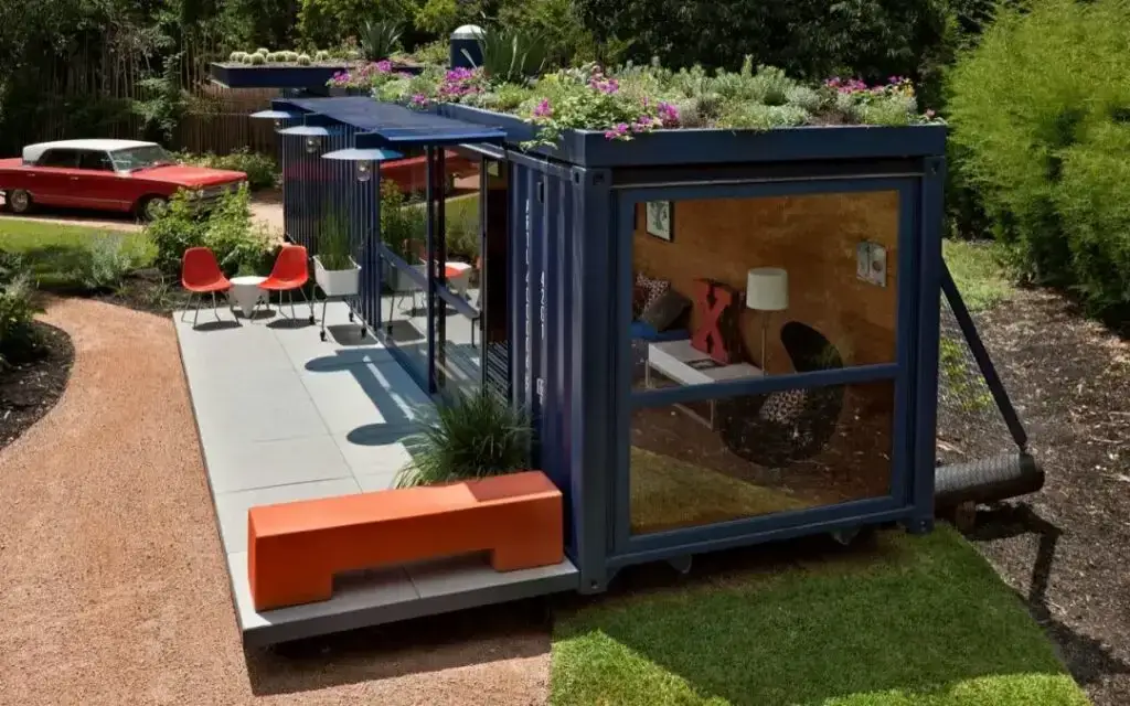 A container house with flowers planted on the roof.