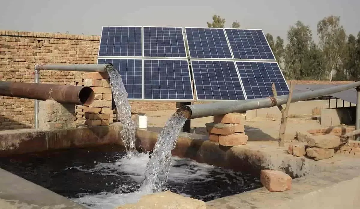 A solar water pump pumping water into a small dam.