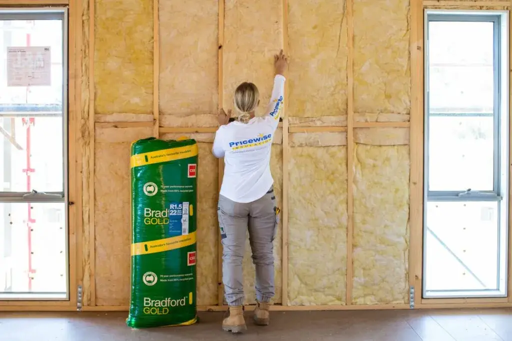 A woman insulating a shipping container house