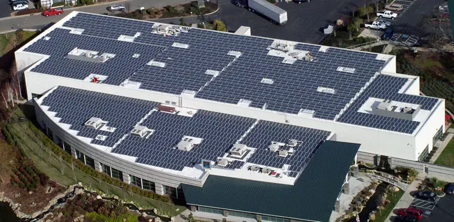 A photo showing several solar panels arranged on top of a large commercial building.